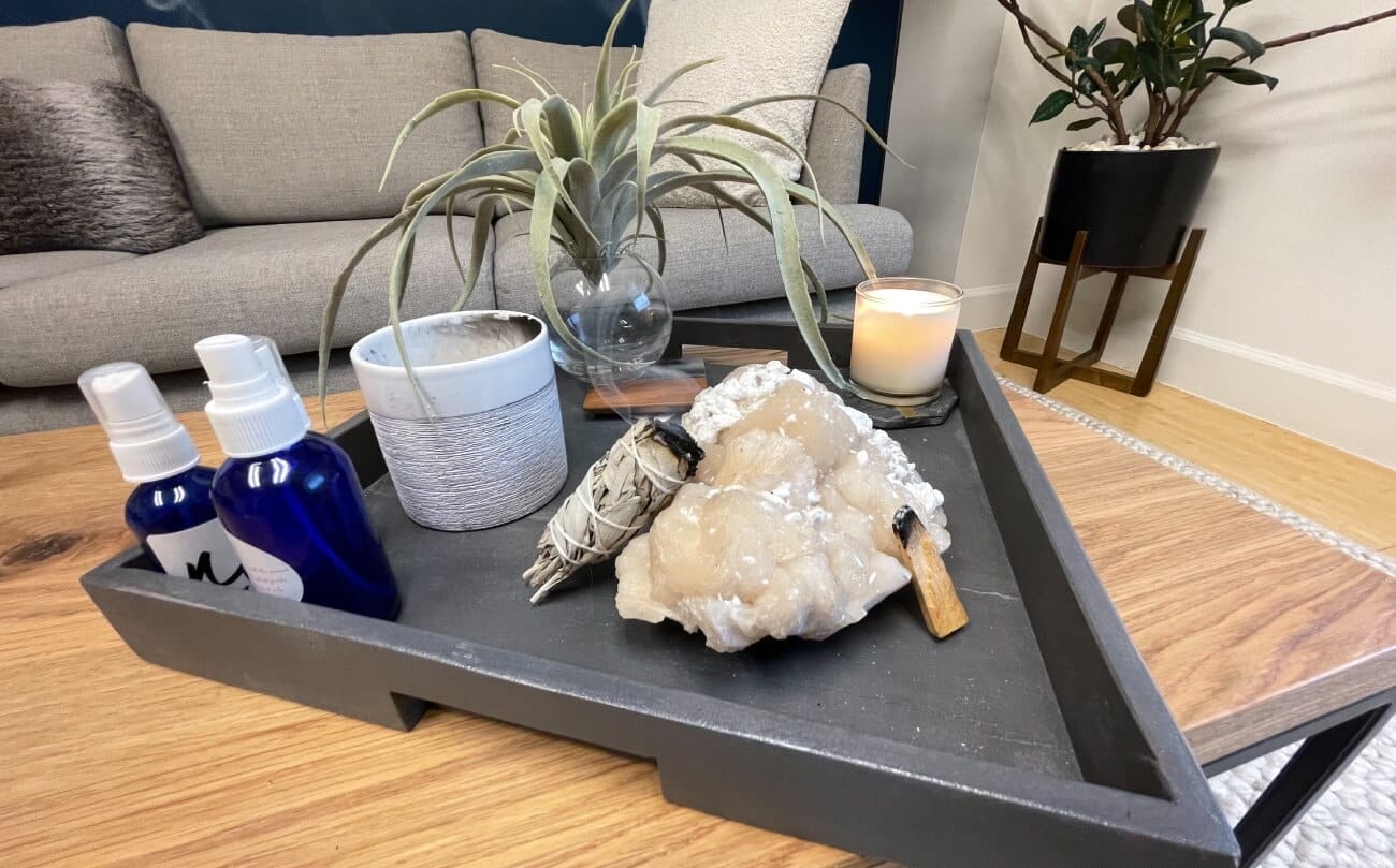 Triangle tray holding a plant, rocks, palo santo, sage, a candle, and room spray to add to the atmosphere in the clinic at K Therapy SLC.