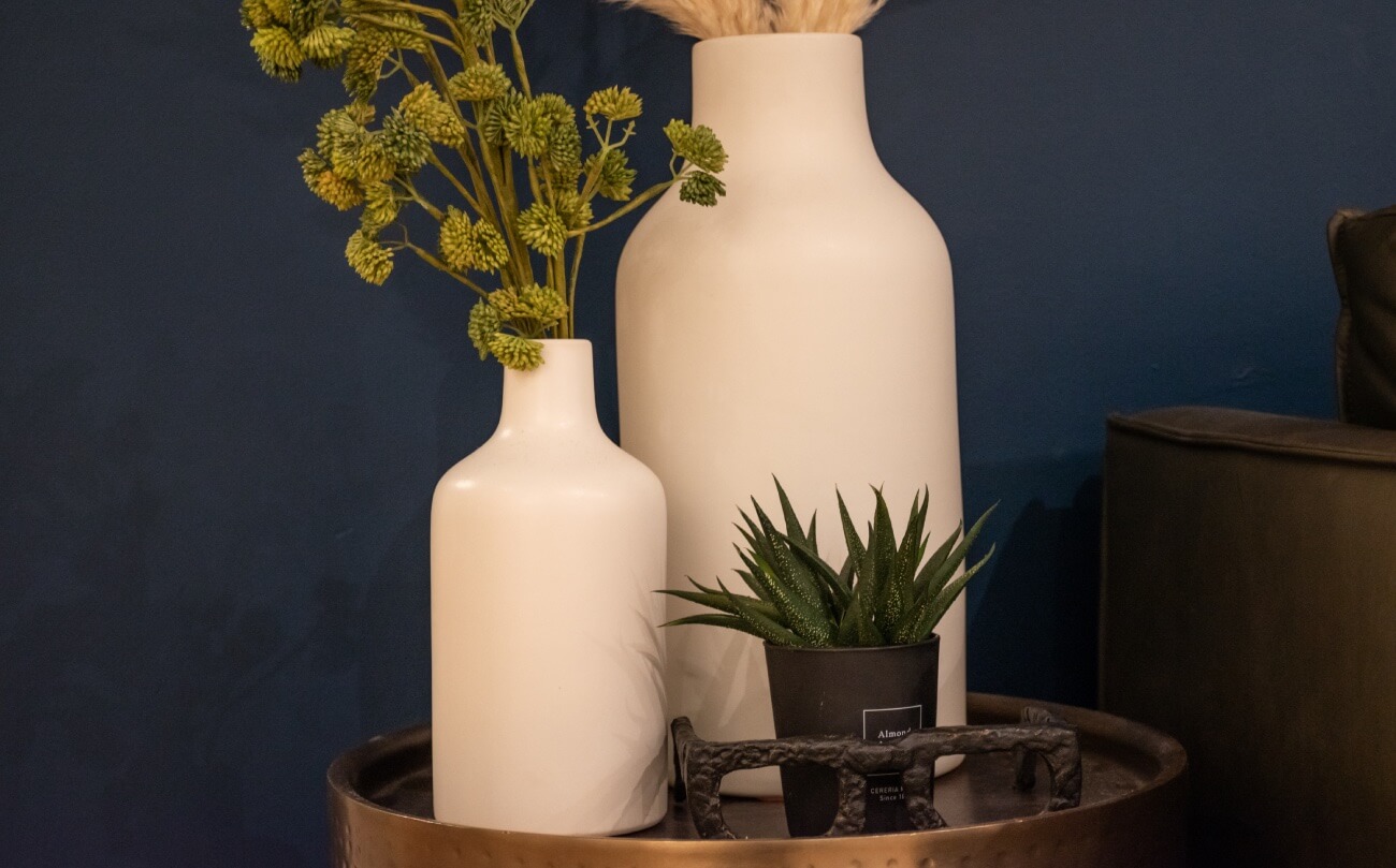 White vases with green plants on an end table against a blue wall, showing the design elements at the clinic at K Therapy SLC.