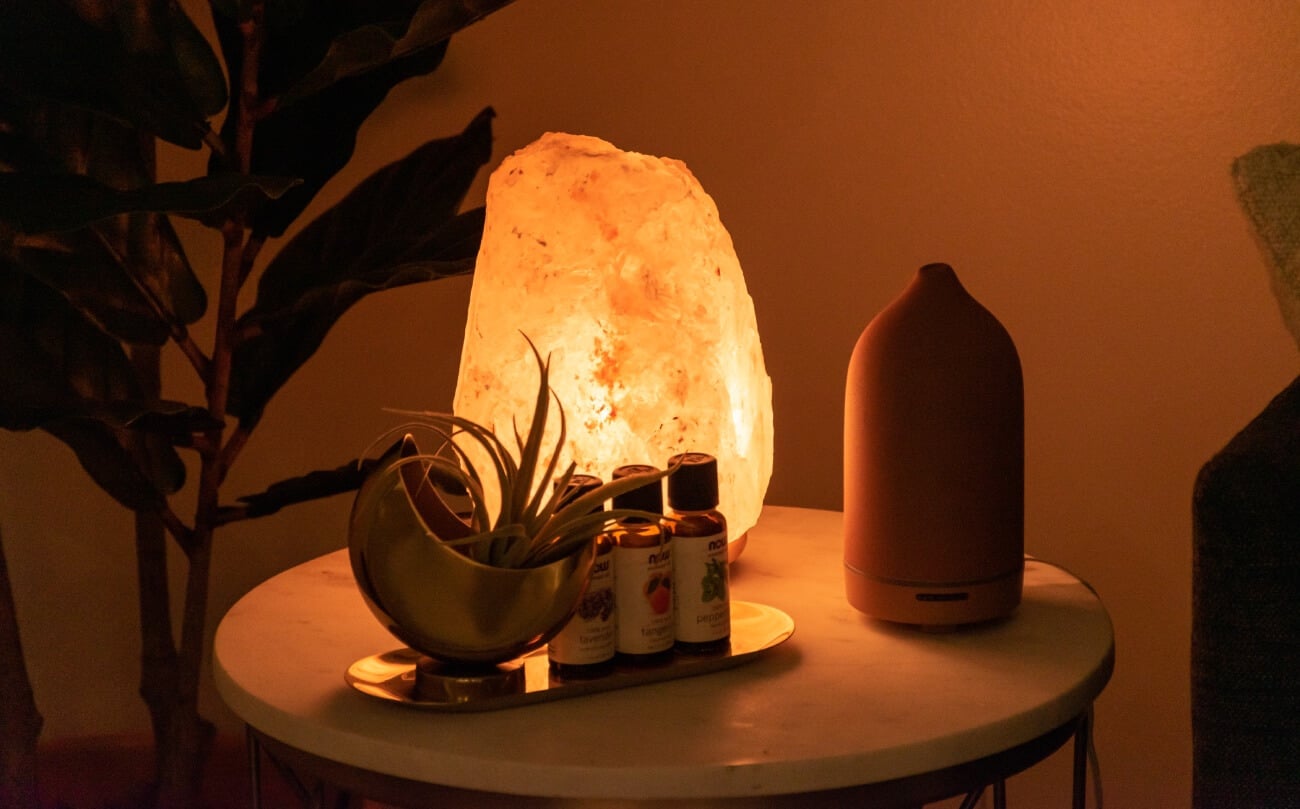 Himalayan Salt Lamp, essential oils, a plant, and a diffuser on an end table at the clinic at K Therapy SLC.