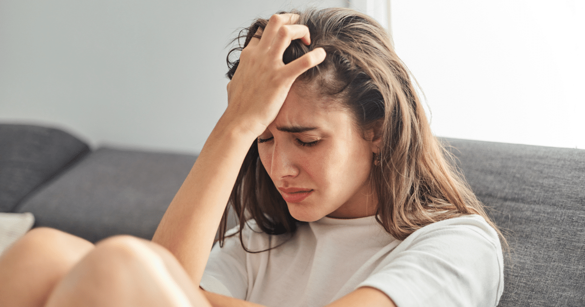 a woman gripping her forehead and hair while experiencing anxiety