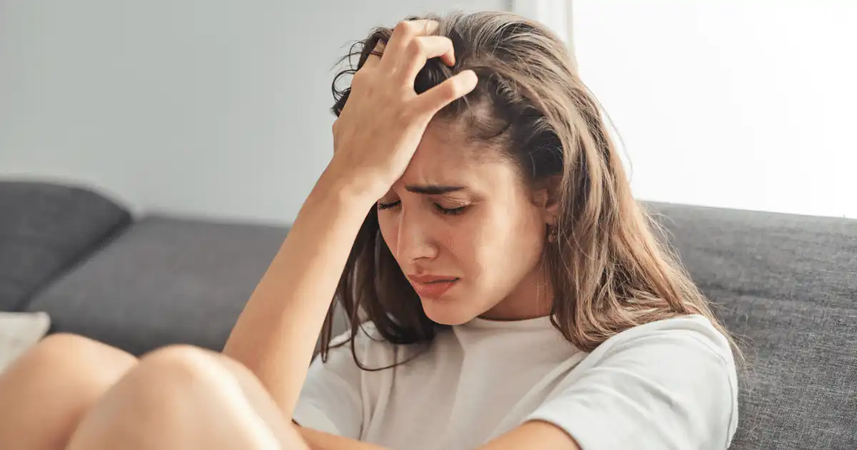 a woman gripping her forehead and hair while experiencing anxiety and in need of 3 alternative anxiety treatments to try.