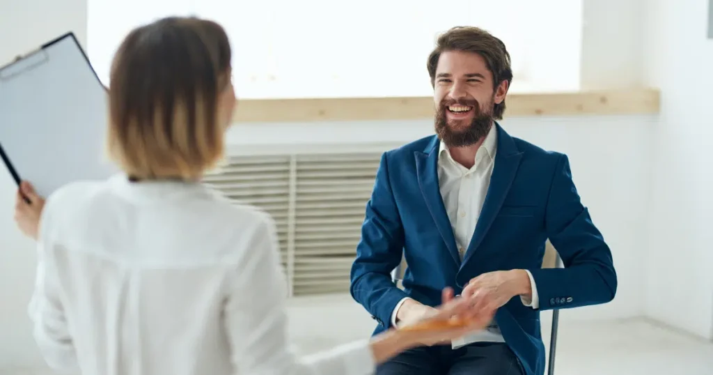 Smiling man standing indoors in a professional setting discussing microdosing ketamine.