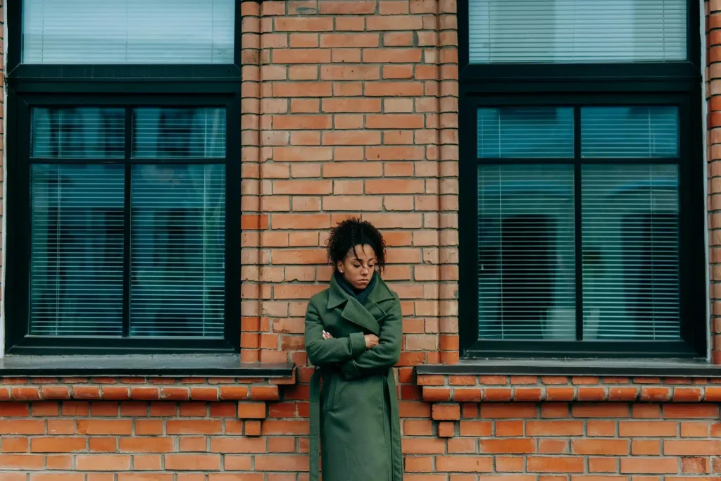 Woman standing in front of a brick wall contemplating ketamine for bipolar depression.