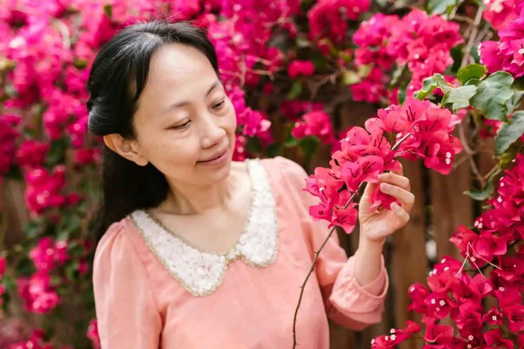 A woman enjoying vibrant pink flowers and considering ketamine for autism.