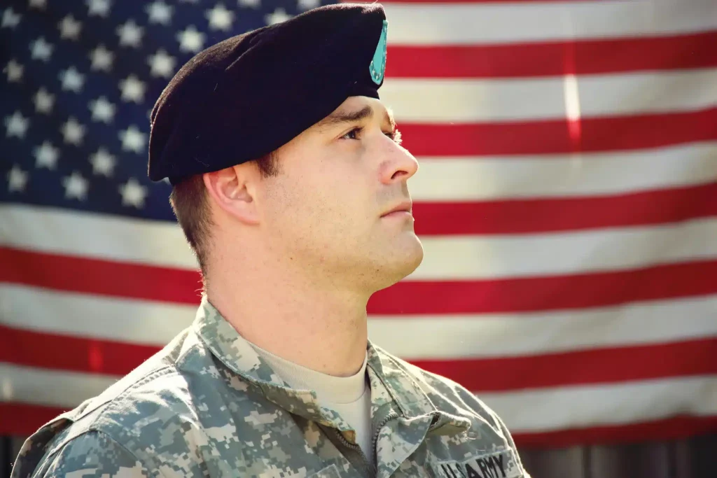 U.S. veteran in uniform stands before the American flag after ketamine for veterans treatment at Ketamine Therapy at Therapeutic Alternatives.